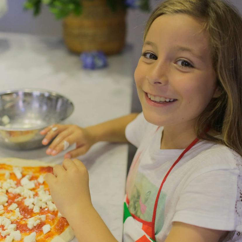 A young girl making her own pizza during the Pizza Masterclass