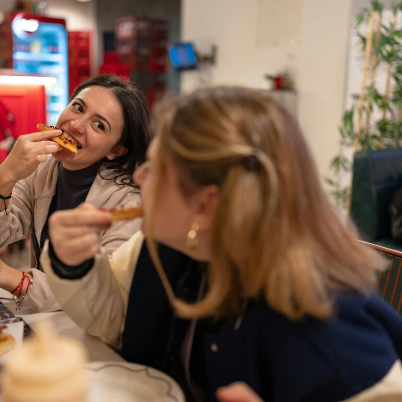 Two young women eating traditional Roman pizza al taglio in Testaccio, Rome