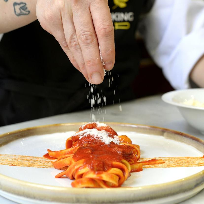 Hand sprinkling cheese over fettuccine all'Amatriciana
