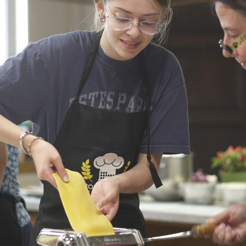girls placing raw pasta dough into pasta maker